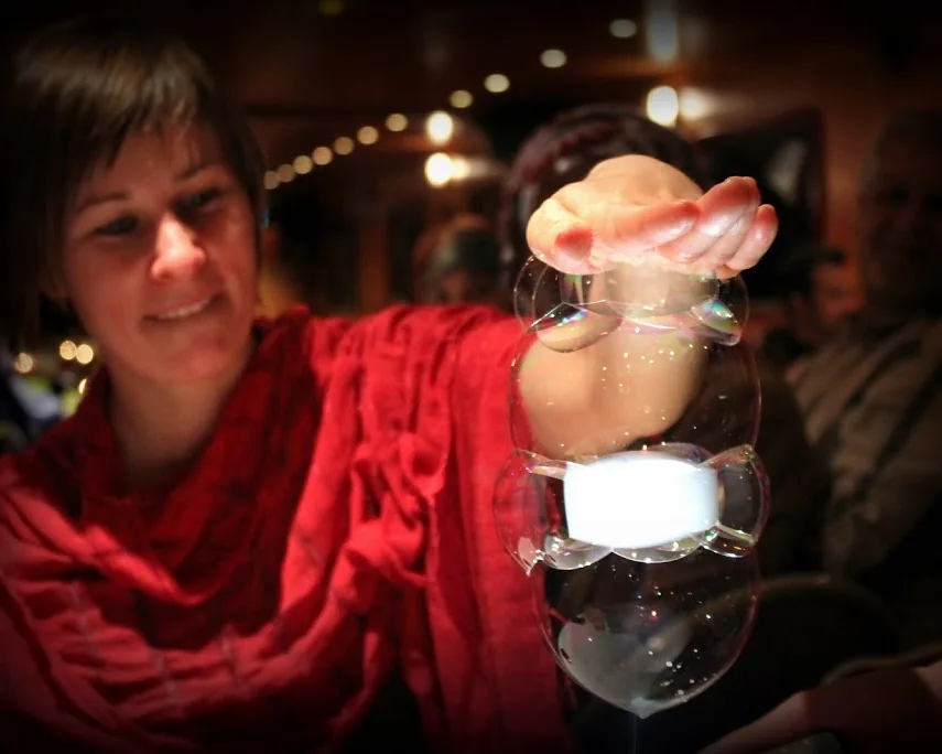 A guest smiles as she receives a tower of bubbles above a glass