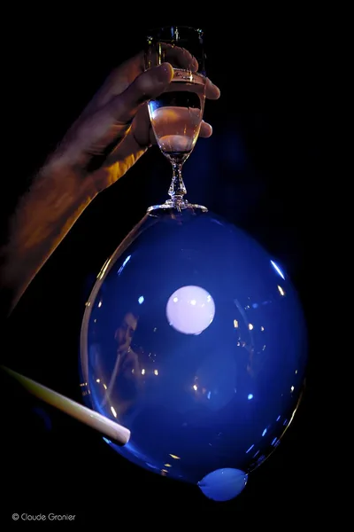 A blue bubble hanging beneath an upturned glass