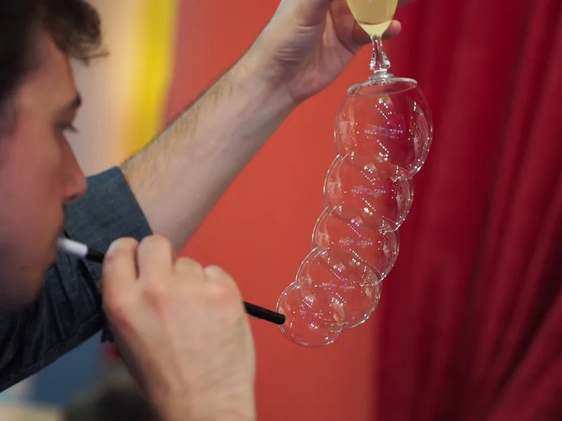 A string of bubbles hanging from a champagne glass