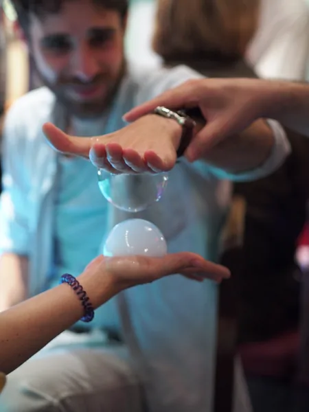Two bubbles resting between a guest's hands
