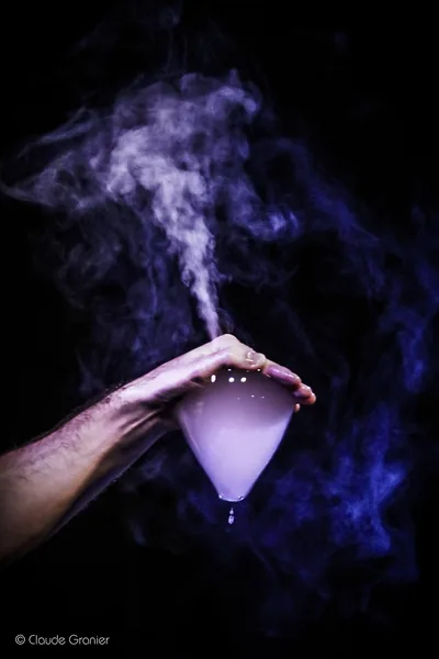 A violet smoke bubble suspended between two hands