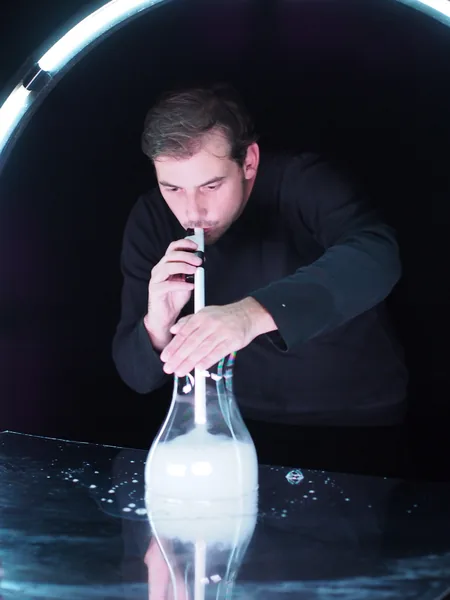Vincent Wüthrich blows into a glass filled with smoke, on a mirrored table