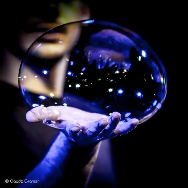 A large blue bubble flecked with reflections, resting in two hands