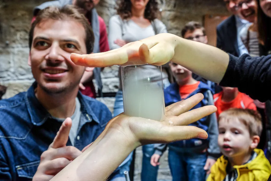 A bubble cylinder held between two hands, in front of onlookers