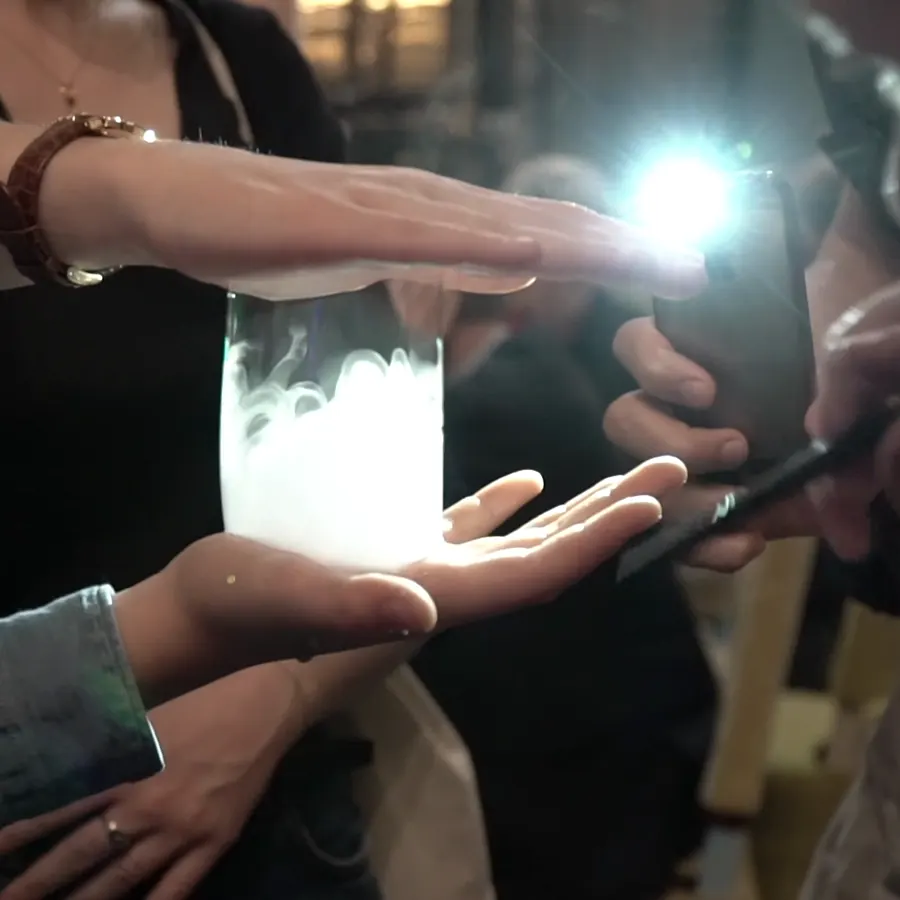 A smoke-filled bubble lights up between guests' hands