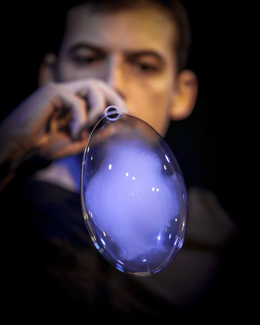 A large blue bubble filled with light, hanging from Vincent Wüthrich's straw