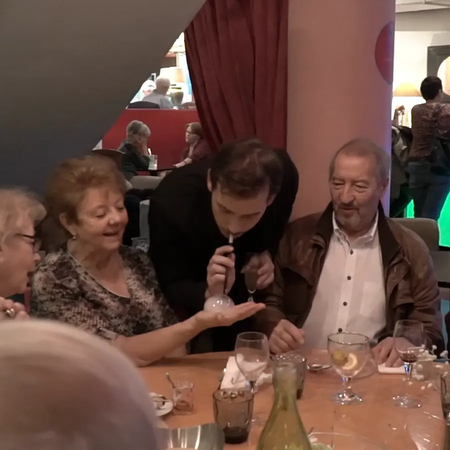 Guests watch a smoke-filled bubble resting in a hand